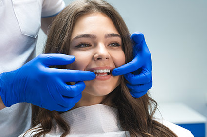 Dentist checking a smiling female patients veneers