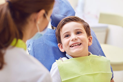 Photo of male child on examination chair smiling with his dentist