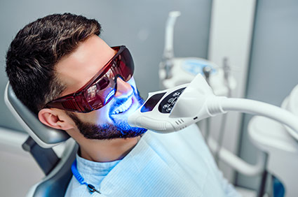 Male patient wearing protecetive UV glasses while having his teeth whitened